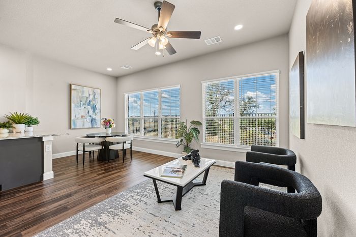 Modern living room with elegant hardwood floors, large windows showcasing scenic views, and a chic dining area with stylish decor.