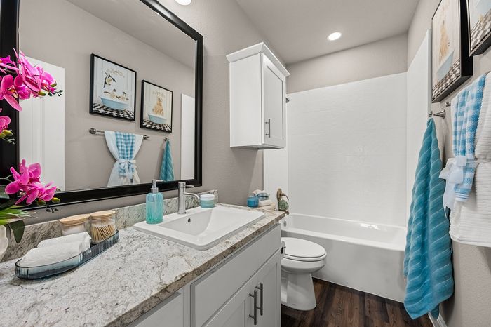 Elegant and modern bathroom with a granite countertop, white vanity, and floral accents, offering a spa-like experience.