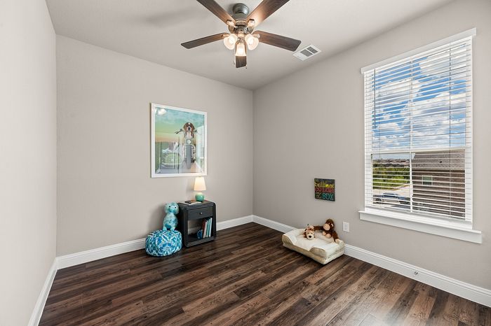 Cozy child's bedroom with plush toys and natural light through wide window featuring serene suburban views.
