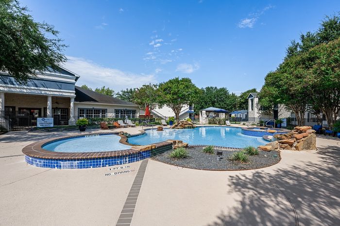 Inviting community pool area with serene landscaping and cozy seating, perfect for relaxation and leisure.