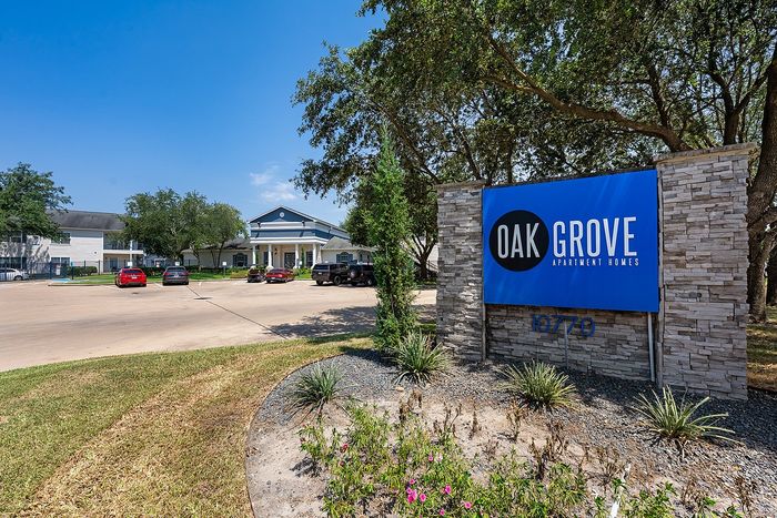 Welcoming entrance to Oak Grove Apartment Homes with lush landscaping and modern signage.