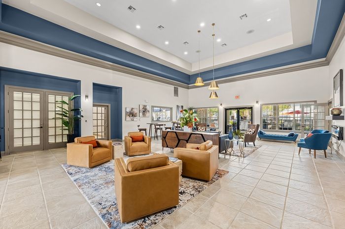 Inviting living space with elegant high ceilings, modern seating, and vibrant decor, perfect for relaxation and entertainment.