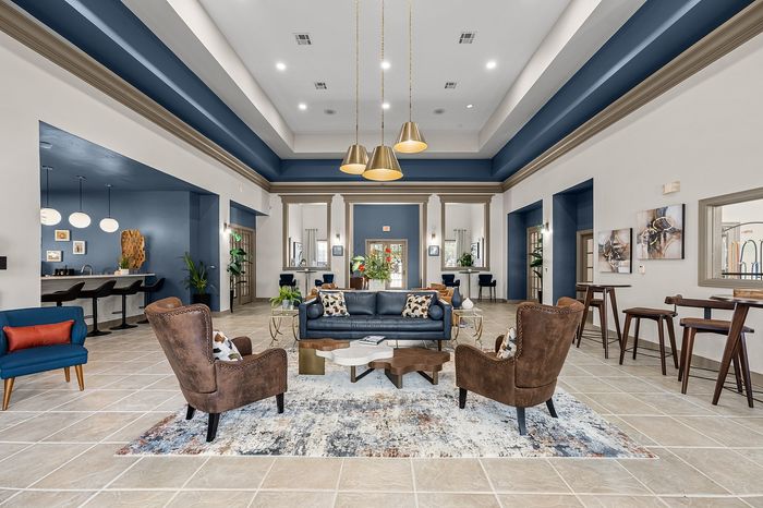 Luxurious and spacious living room with sophisticated blue accents, elegant lighting fixtures, cozy seating arrangements, and modern decor.