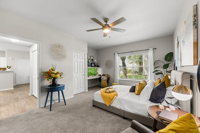 Inviting bedroom with cozy decor, showcasing large windows with garden views, a stylish desk nook, and vibrant accents.
