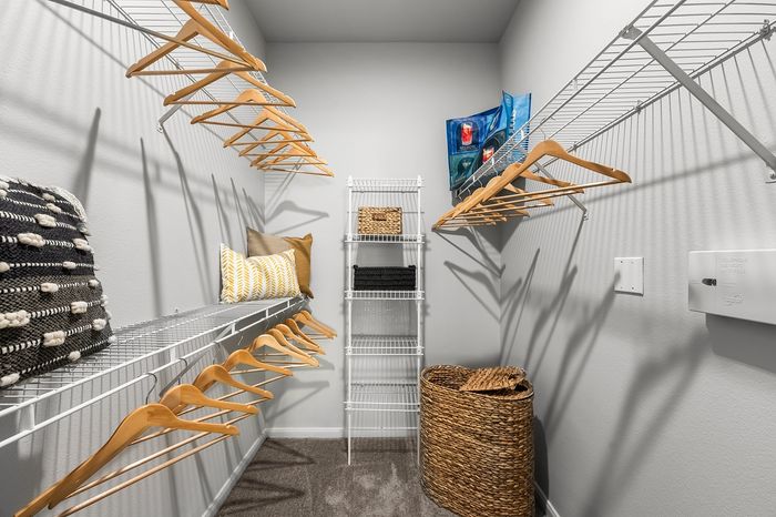 Spacious and organized walk-in closet with stylish shelving, natural wicker baskets, and ample wooden hangers under soft lighting.