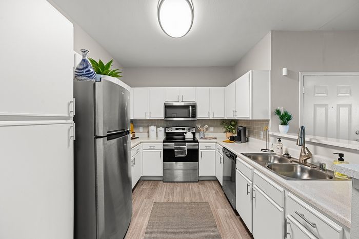 Modern kitchen with sleek stainless steel appliances, stylish white cabinetry, and elegant lighting, showcasing a spacious and inviting cooking area.