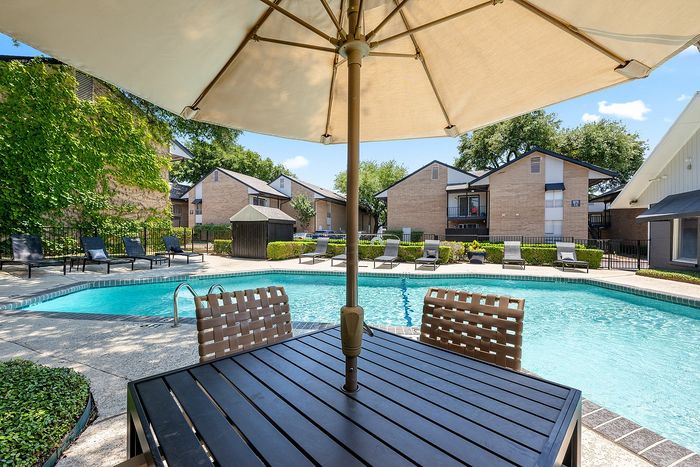 Inviting poolside oasis with stylish lounge chairs and well-maintained landscaping, perfect for relaxation and outdoor enjoyment.
