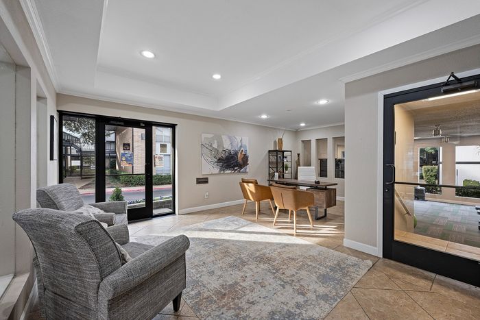 Inviting apartment lobby with modern furniture, stylish artwork, and natural light streaming in through large glass doors.