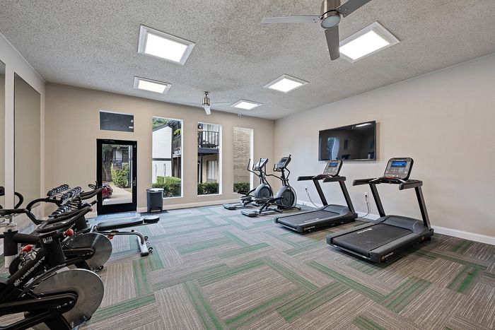 Bright and modern fitness center with state-of-the-art treadmills and exercise bikes, offering natural light and sleek design.