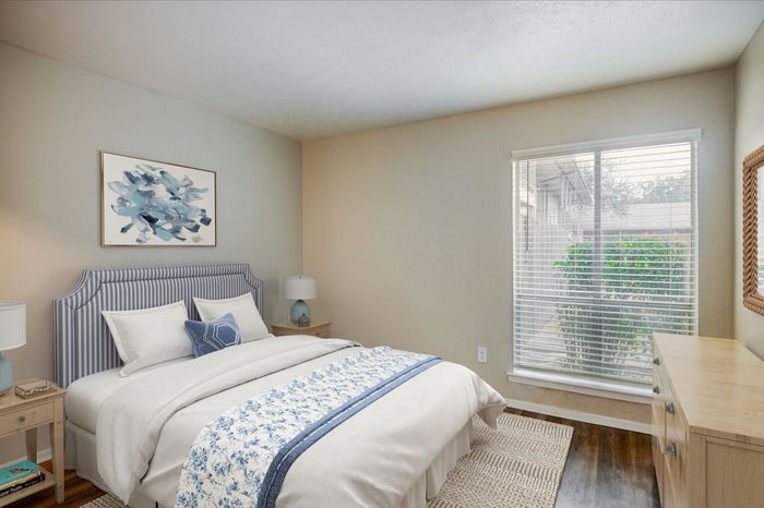 Charming bedroom with elegant striped headboard, cozy bedding, and large window infusing natural light.