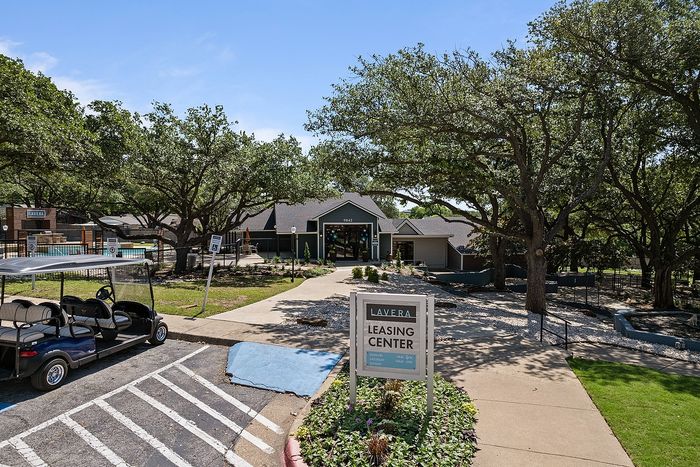 Inviting entrance to Lavera Leasing Center surrounded by lush greenery and a welcoming path.
