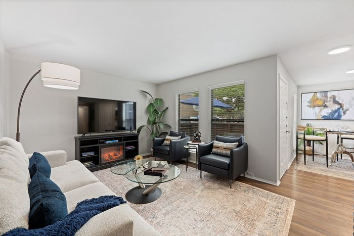 Inviting living room with plush sofa, modern decor, and large windows offering natural light, seamlessly connected to a chic dining area.