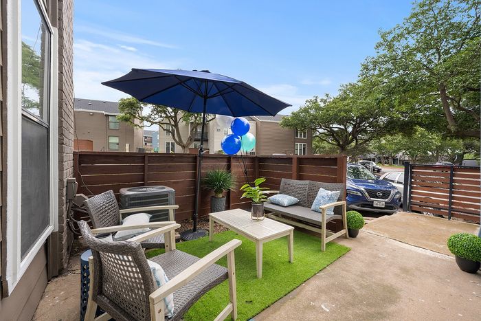 Charming outdoor patio featuring stylish seating, vibrant plants, and a large blue umbrella, perfect for relaxation.