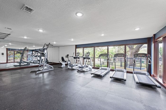 Modern fitness center with state-of-the-art equipment and large windows overlooking serene greenery.