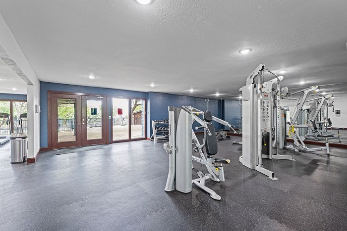 Modern fitness center with state-of-the-art gym equipment and large windows offering abundant natural light.