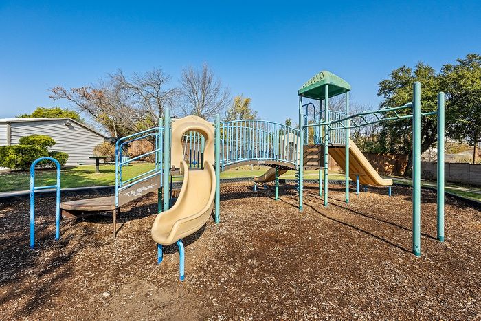 Inviting playground with colorful slides and climbing structures, nestled in a serene outdoor setting, perfect for family fun and relaxation.