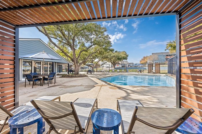 Inviting outdoor pool area surrounded by lush greenery and modern lounge chairs, perfect for relaxation and leisure.