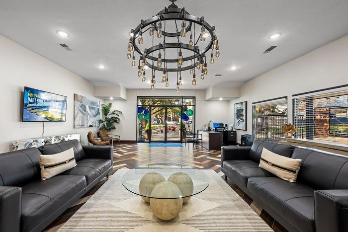 Inviting apartment lobby with modern leather sofas, artistic lighting, and stylish decor, offering a warm and welcoming atmosphere.