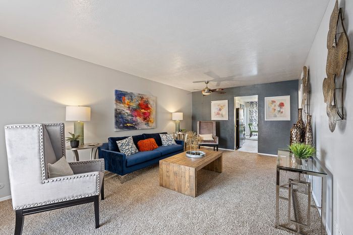 Inviting living room with elegant decor, featuring a plush blue sofa, vibrant artwork, and cozy ambiance.
