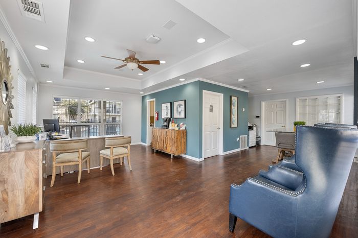 Modern apartment lobby with elegant wooden flooring, stylish seating, and a welcoming reception area bathed in natural light.