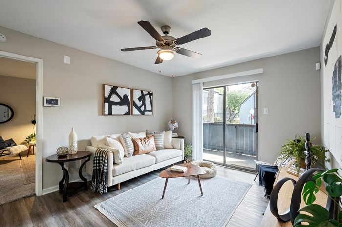 Chic living room with modern decor, featuring a cozy white sofa, abstract wall art, and large sliding glass doors opening to a balcony view.