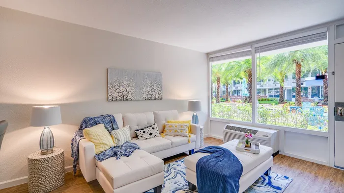 Bright and inviting living room with stylish decor, cozy white sofas, and large windows showcasing lush garden views.