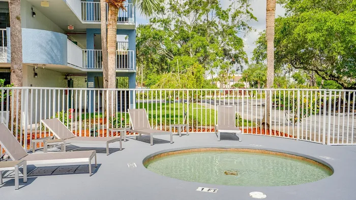 Refreshing outdoor pool area with modern lounge chairs surrounded by lush greenery and stylish architecture.