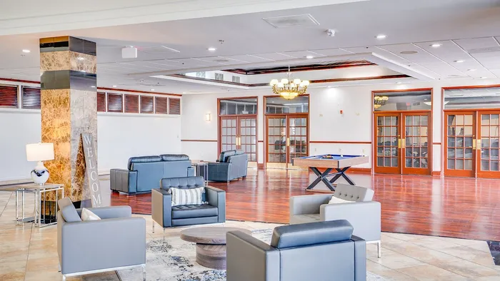 Spacious and elegant lounge area with modern seating, a warm welcome sign, and polished hardwood floors, ideal for relaxation and social gatherings.