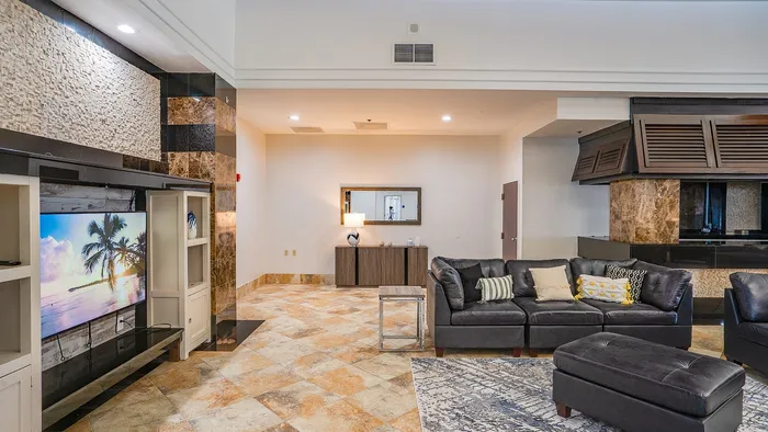 Luxurious living space with leather sectional, elegant marble accents, and wall-mounted TV showcasing tropical scenery.