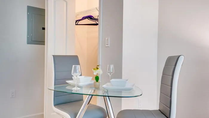 Elegant and cozy dining area with a modern glass table set for two, offering a stylish touch to apartment living.