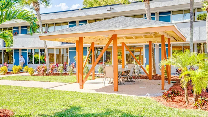 Charming outdoor gazebo area within a vibrant apartment complex, featuring lush landscaping and inviting seating, perfect for relaxation and social gatherings.