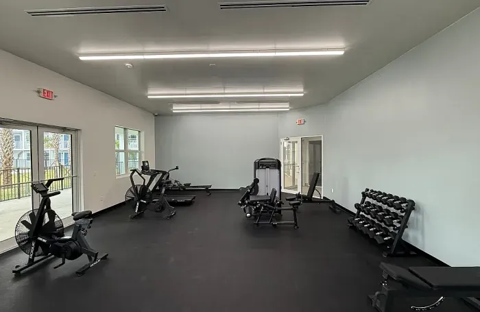 Modern fitness center with large windows and a row of cardio equipment.