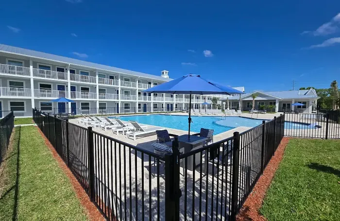 Modern three-story apartment complex exterior with striking blue doors and a bright blue sky.