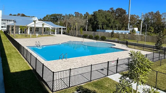 Inviting outdoor pool area surrounded by lush greenery and a stylish fence, perfect for relaxation and leisure.