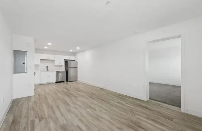 Modern furnished apartment living room with a gray sofa, coffee table, and a view into the kitchen.