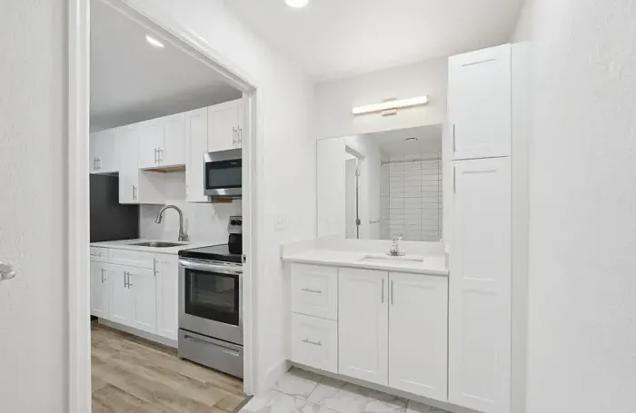 Modern apartment kitchen featuring stainless steel appliances, dark countertops, and white cabinetry.