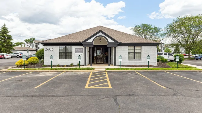 Charming office building with inviting entrance and abundant parking, surrounded by lush greenery.
