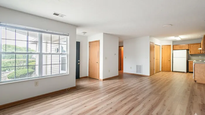 Bright, open-concept living area with large windows, wood flooring, and a modern kitchen, perfect for stylish living.