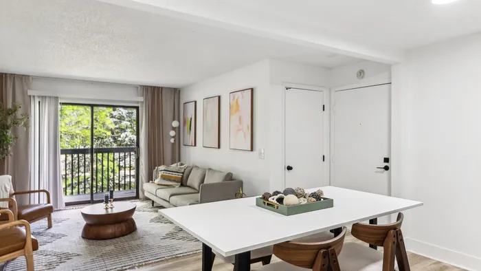 Bright and modern living space with a stylish lounge area, chic dining table, and large sliding glass doors opening to a lush garden view.