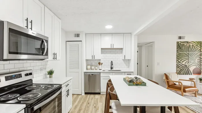 Contemporary kitchen with sleek white cabinets, stainless steel appliances, and a stylish breakfast bar in a bright, open-concept layout.