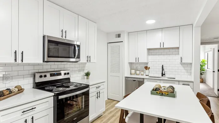 Modern kitchen with sleek white cabinetry, stainless steel appliances, and a spacious island, ideal for culinary enthusiasts.