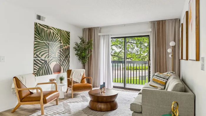 Bright and welcoming living room with stylish decor, cozy seating, and floor-to-ceiling windows overlooking lush greenery.