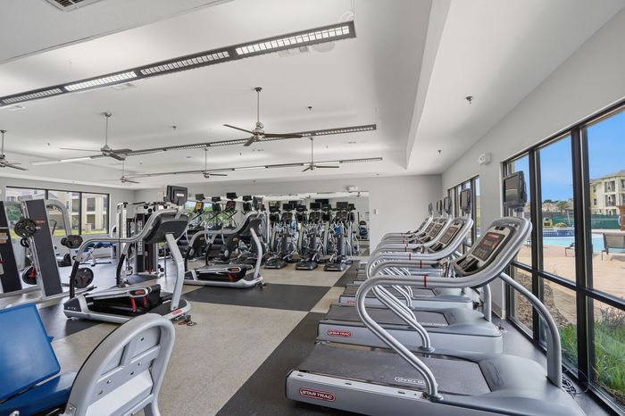 Spacious modern gym featuring state-of-the-art treadmills, strength machines, and ample natural light, perfect for an invigorating workout.