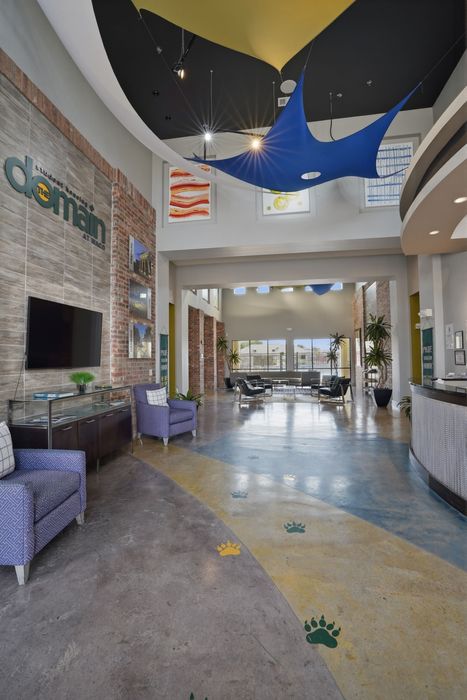 Modern lobby with vibrant decor, featuring stylish seating, floor art, and natural light pouring through large windows.