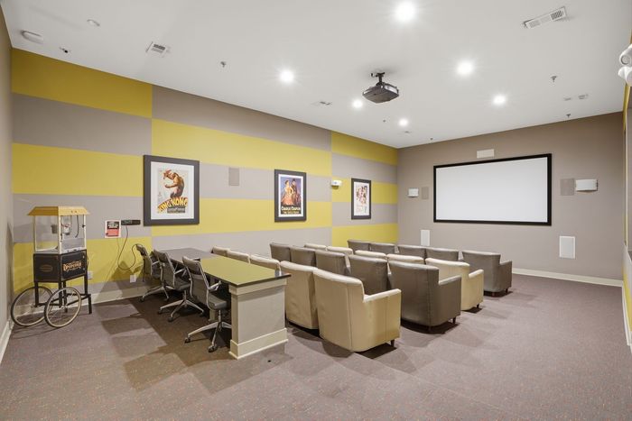 Theater room featuring plush seating, a large screen, and vibrant wall decor, perfect for cinematic experiences.