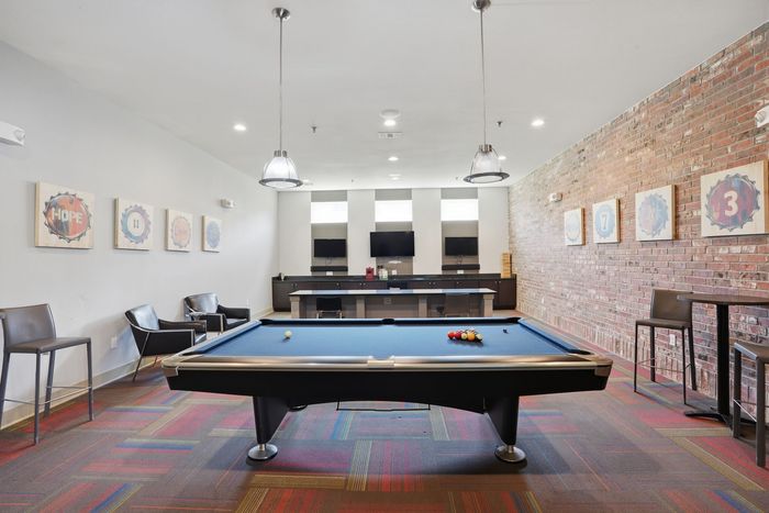 Chic recreational room featuring a modern pool table, vibrant carpet, and stylish seating.