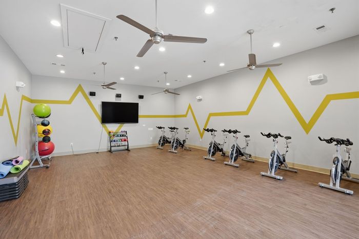 Modern fitness room equipped with stationary bikes and colorful exercise balls.