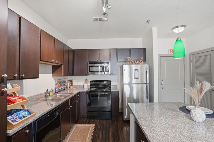 Modern kitchen with dark wood cabinets, sleek countertops, and stainless steel appliances.