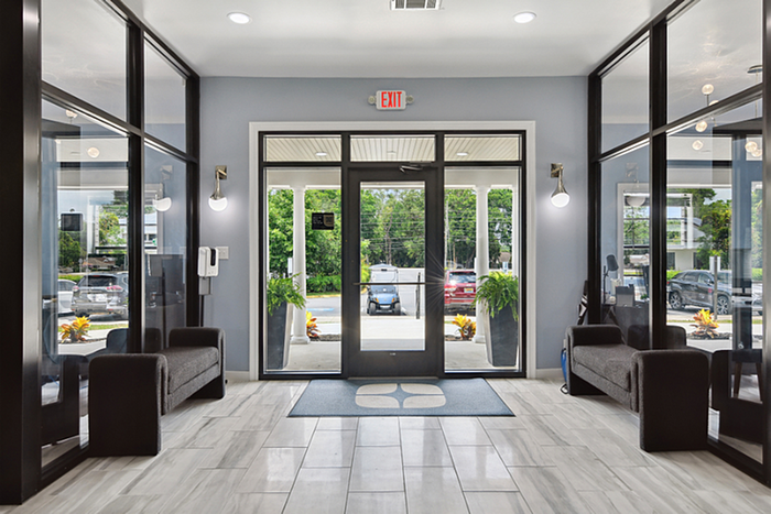 Sleek and modern apartment lobby with inviting seating, large windows, and elegant tile flooring.