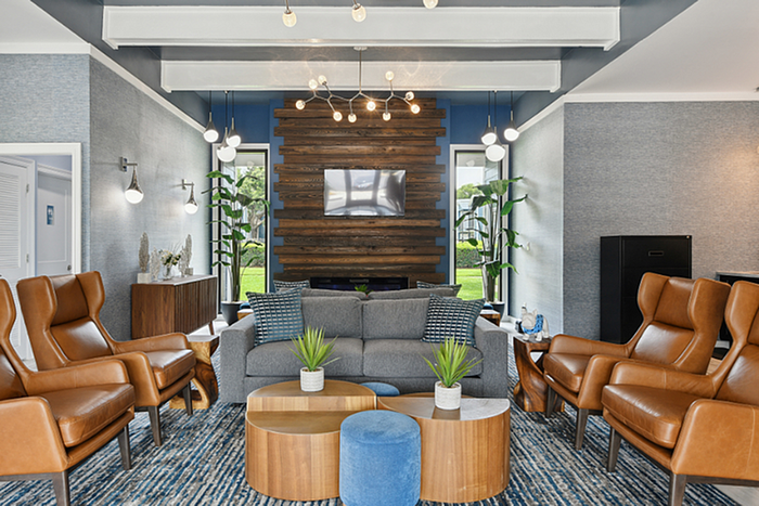 Elegant living room with stylish gray sofa, chic leather armchairs, and modern wood wall accent piece.